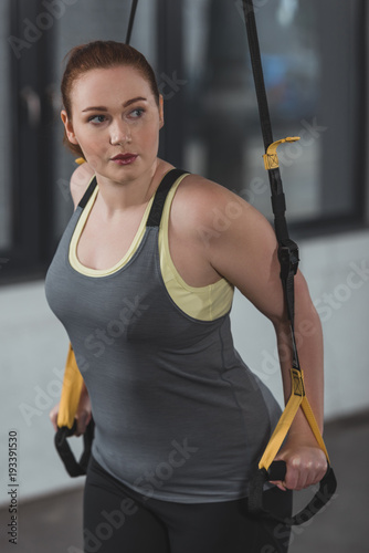 Overweight girl training on suspension straps in gym © LIGHTFIELD STUDIOS