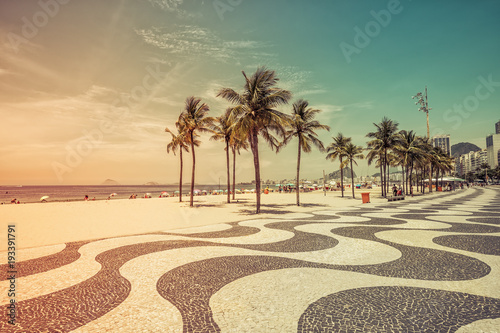 Sunny day with palms by Copacabana Beach mosaic boardwalk, Rio de Janeiro. Vintage colors with light leak