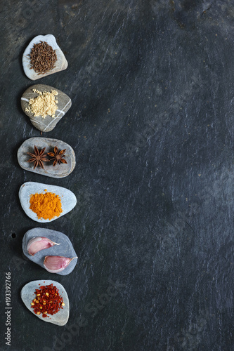 Colorful spices on pebbles in a line with copy space to the right