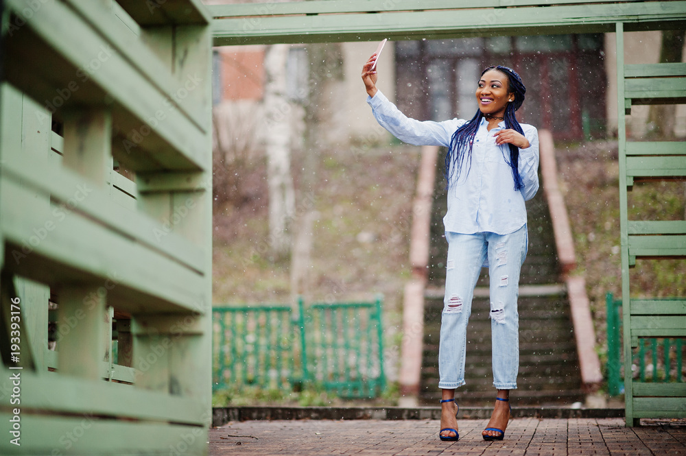 Stylish african american girl with dreads holding mobile phone at hand, outdoor snowy weather. Stylish african american girl with dreads holding mobile phone at hand, outdoor snowy weather.