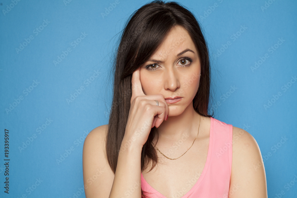 young woman looks suspiciously on a blue background young woman looks suspiciously on a blue background