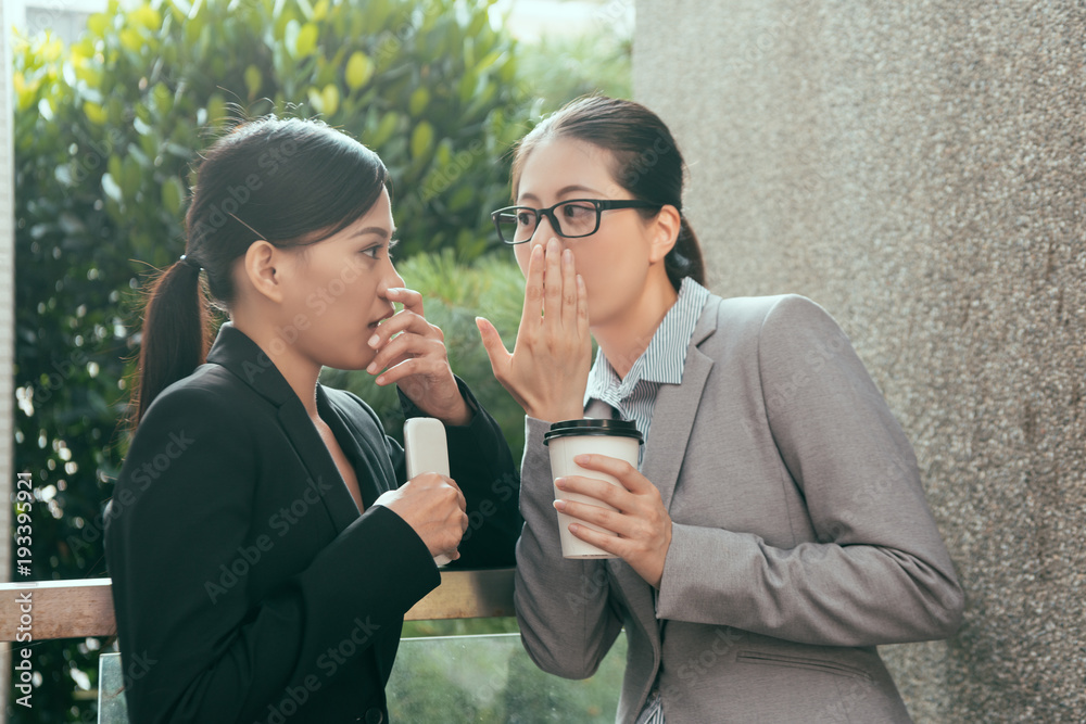 Asian women talking about office gossip Asian women talking about office gossip