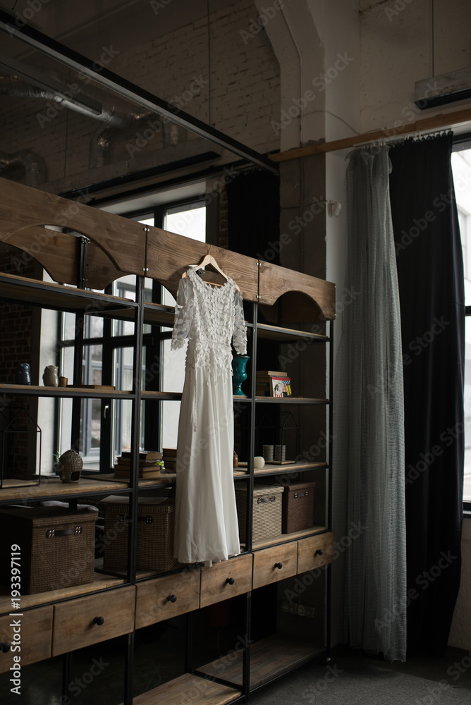 Rustic white wedding dress hanging on the cupboard. Loft interior Rustic white wedding dress hanging on the cupboard. Loft interior