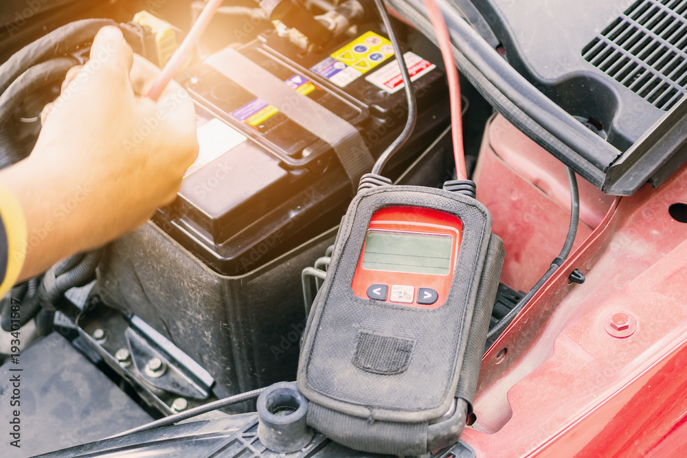 car mechanic use voltmeter to check car battery voltage level