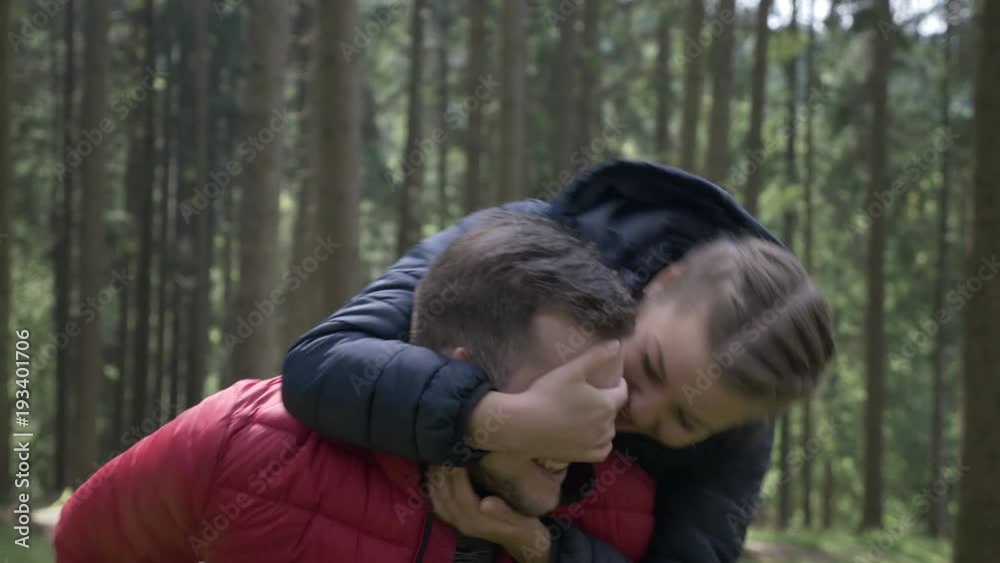 Closeup of loving girlfriend jumping on the boyfriend back kissing and caressing him while they enjoying the excursion in the nature Closeup of loving girlfriend jumping on the boyfriend back kissing and caressing him while they enjoying the excursion in the nature