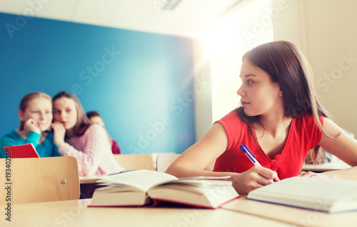 Фотография students gossiping behind classmate back at school