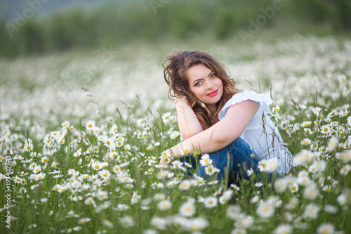 Beautiful woman on the camomile field is wearing white dress, spring time
