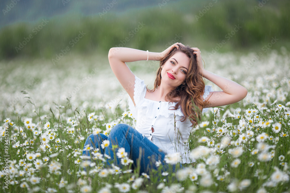 Beautiful happy smiling woman on the camomile field is wearing white dress, spring time