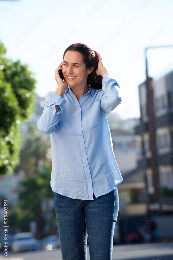 smiling middle aged woman walking and talking on cellphone smiling middle aged woman walking and talking on cellphone