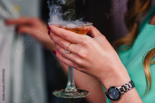 woman's hand with a Martini glass with bubbles and steam close-up
