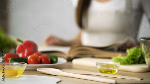 Close-up of girl flipping through cooking book pages  choosing salad recipe