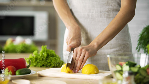 Female chef cutting lemon with sharp knife for lunch preparing  cooking tips