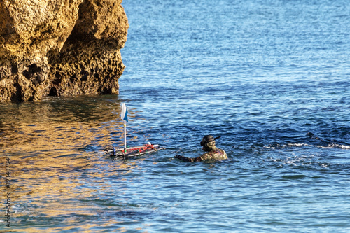 Underwater hunter, on surface, adjusts buoy with harpoons and crossbows.