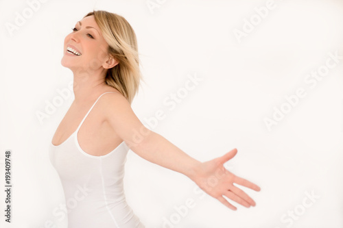 Giovane donna felice e spensierata esultante con le braccia aperte, sorridente, gioiosa, in estasi con occhi semi chiusi. Isolata su sfondo bianco in studio photo