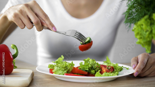 Woman eating vegetable salad, observing diet and counting calories, wellness