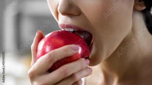Foto Hungry girl with great appetite biting big juicy apple, healthy snack at work