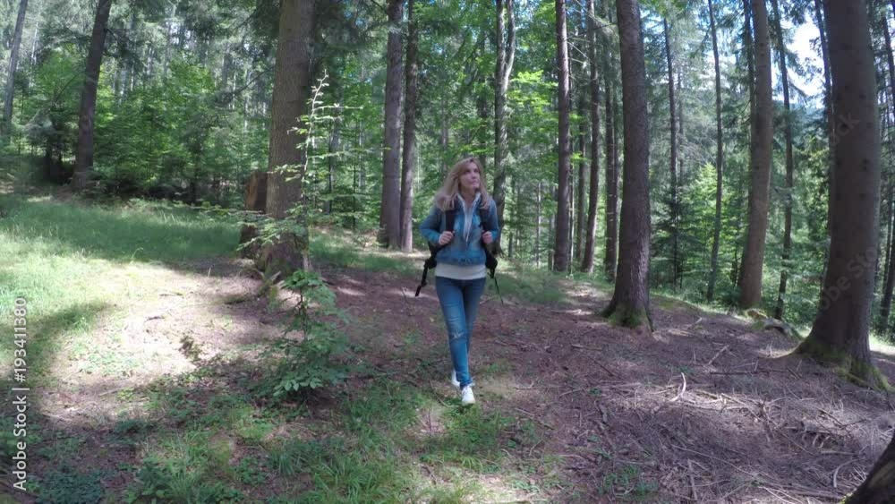 Eco friendly young woman walking alone in forest admiring nature on sunny day Eco friendly young woman walking alone in forest admiring nature on sunny day