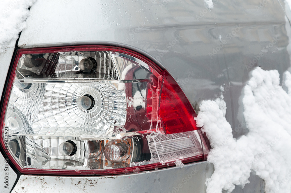 Damaged and broken rear stop or tail light of the silver car in crash accident in the winter on
