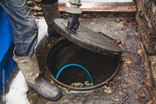 hand opens sewer hatch in yard photo
