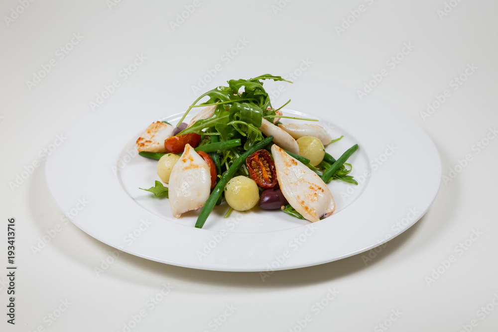 Seafood Salad with tomato and calamari on a white plate on a white background isolated