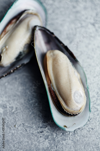 Close up image of raw kiwi mussels on textured light colored background