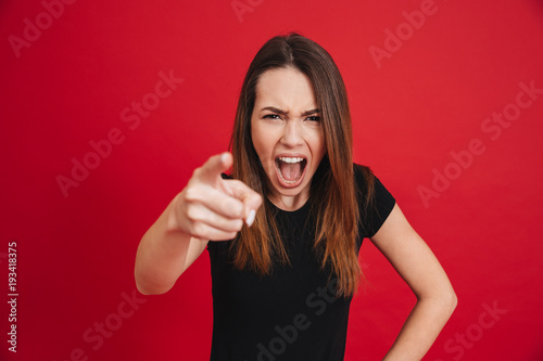 Fotografie Portrait of emotional pretty woman in black t-shirt screaming and pointing index
