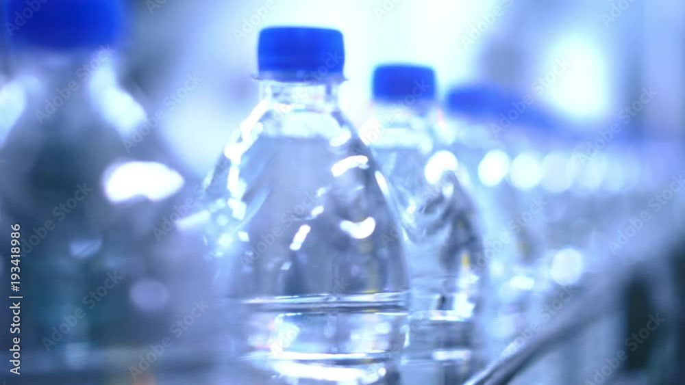 Clean water in plastic bottle moves through conveyor factory.