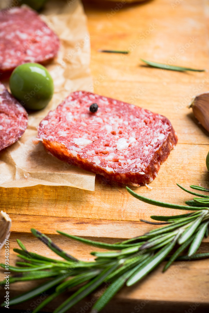 Delicious salami with olives, spices and rosemary. Selective focus.