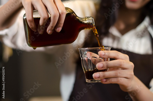 women hand pouring cold coffee into a glass.cold brew coffee,