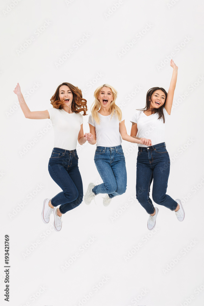 Full length portrait of three joyful casual girls jumping