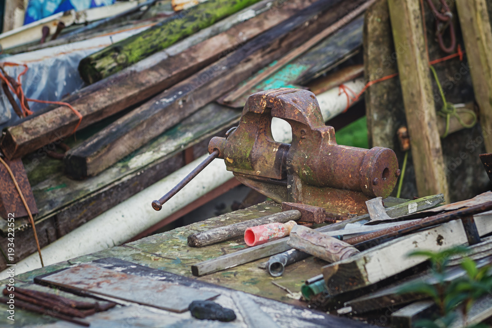 Rusted vise and hammer between the waste wood Rusted vise and hammer between the waste wood