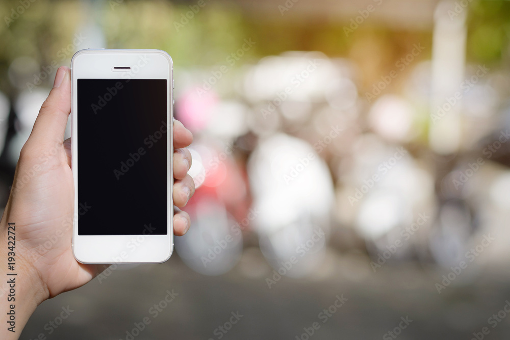 hand holding smartphone on abstract bokeh background