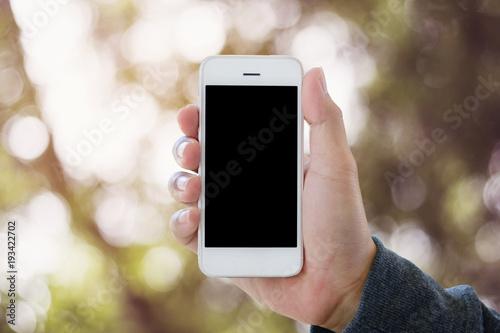 hand holding smartphone on abstract bokeh background