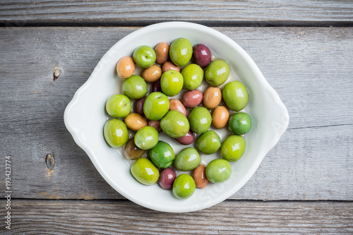 Fresh olives in white plate on the rustic background. Selective focus.