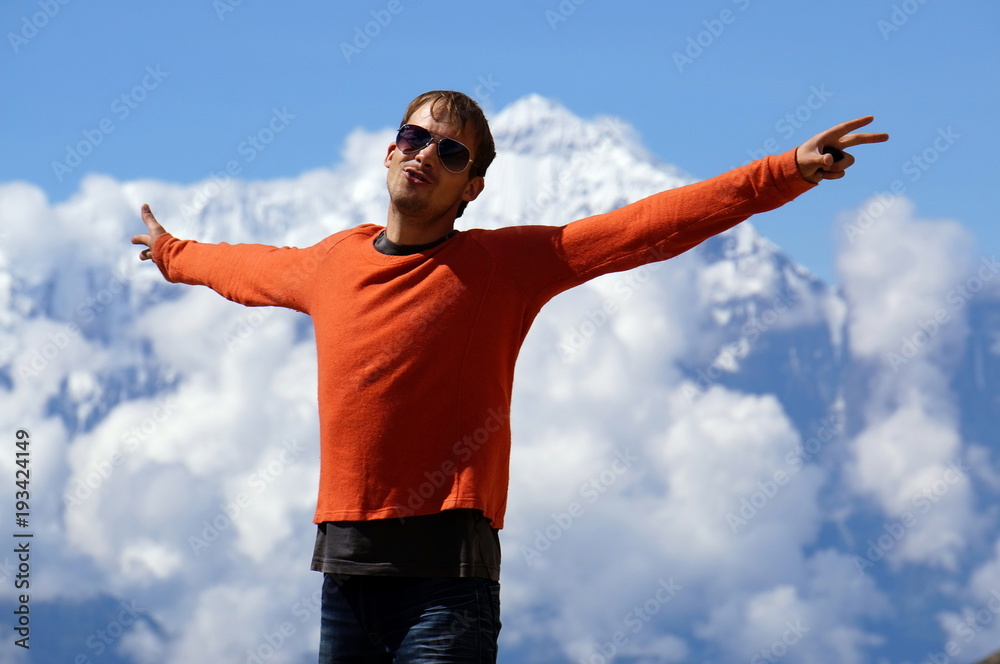 Young man is standing, spread his arms wide, against the backdrop of the Annapurna massif. Trekking to the Upper Mustang. Nepal. Young man is standing, spread his arms wide, against the backdrop of the Annapurna massif. Trekking to the Upper Mustang. Nepal.