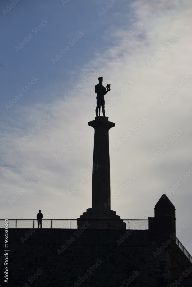 Man standing next to statue of Victory in Belgrade, Serbia