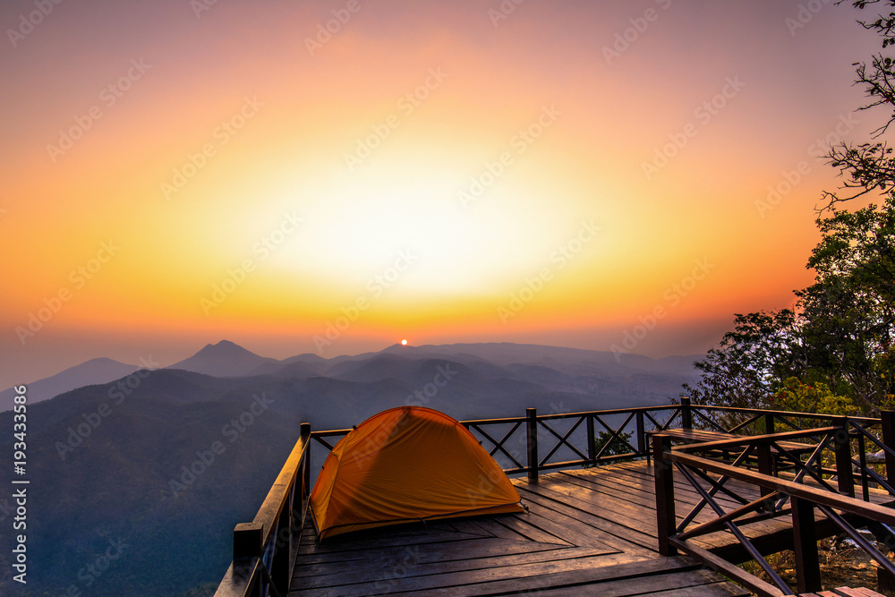 The orange hiker's  tent on the wooden terrace in  high mountain.