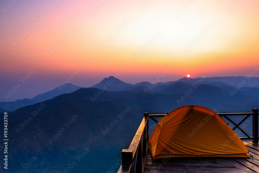 The orange hiker's  tent on the wooden terrace in  high mountain.