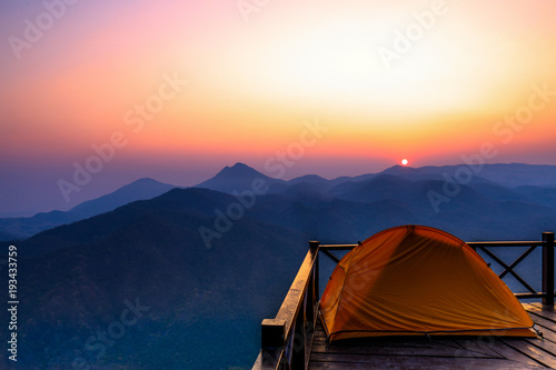 The orange hiker's tent on the wooden terrace in high mountain.