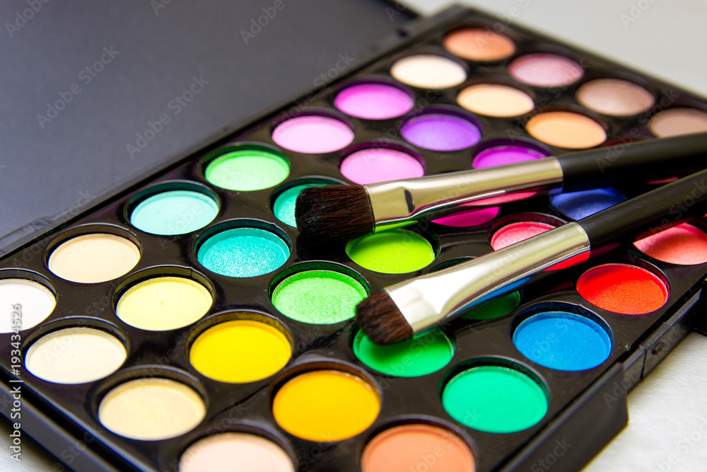 Brushes with an eyeshadow palette and lipstick in серебристом background. Decorative cosmetics for professional makeup. Eyeshadow colors trend. Brushes with an eyeshadow palette and lipstick in серебристом background. Decorative cosmetics for professional makeup. Eyeshadow colors trend.