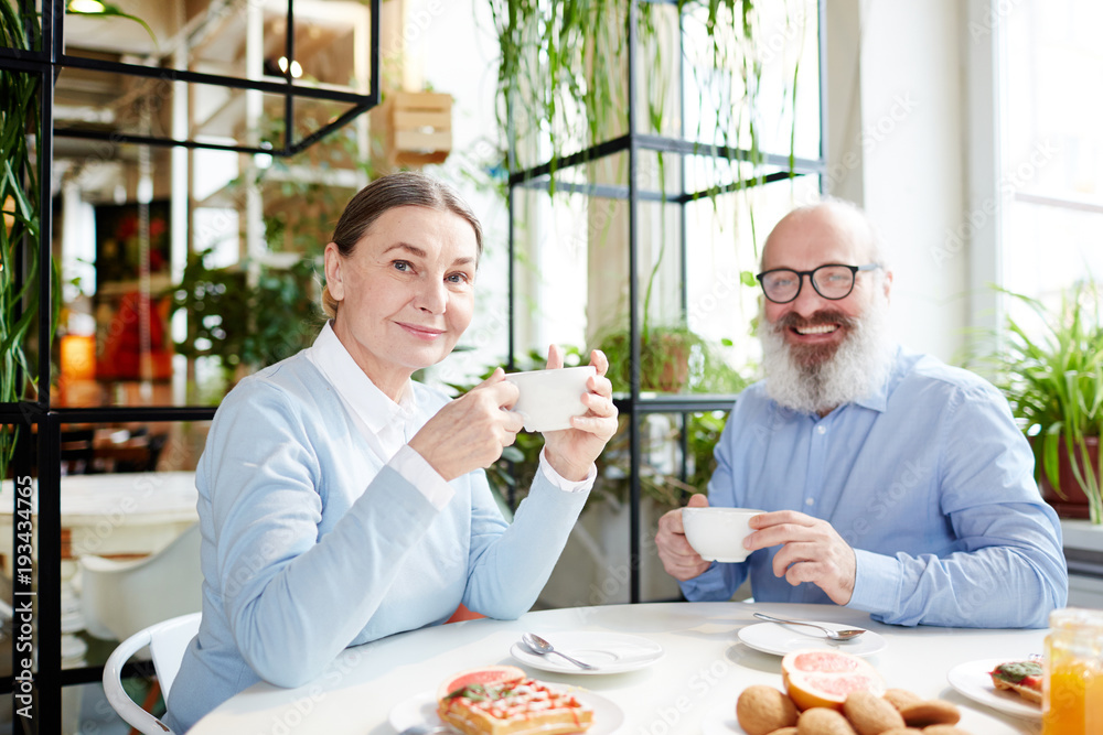 Happy senior man and woman enjoying aromatic tea and yummy dessert in cafe Happy senior man and woman enjoying aromatic tea and yummy dessert in cafe