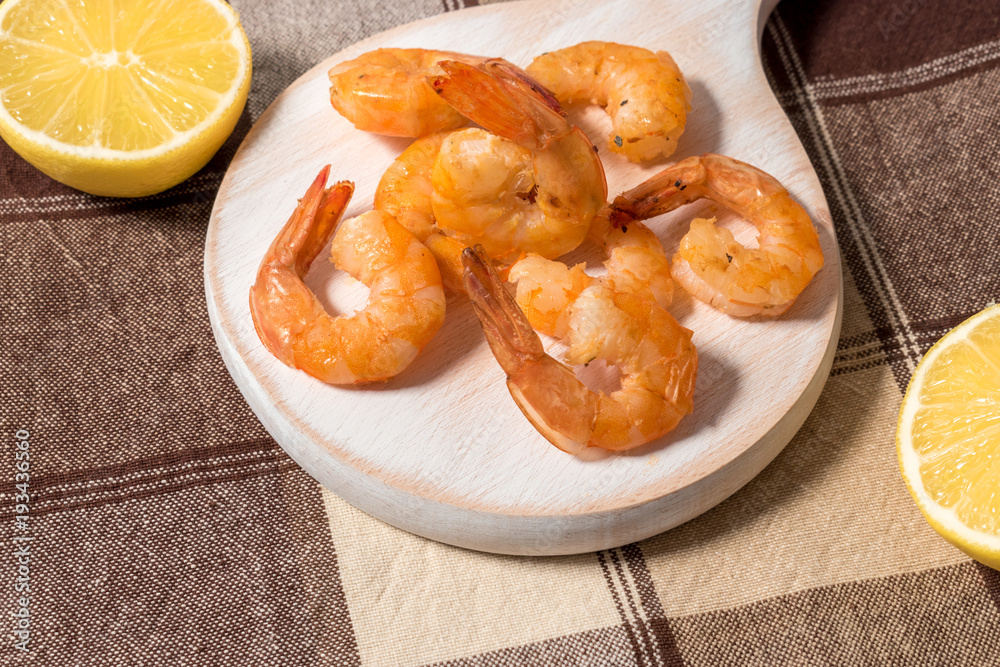 Grilled shrimps with lemon, paprika, spices and herbs on a white wooden board. Grilled shrimps with lemon, paprika, spices and herbs on a white wooden board.