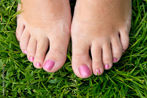 Female feet with a beautiful manicure on a background of green grass