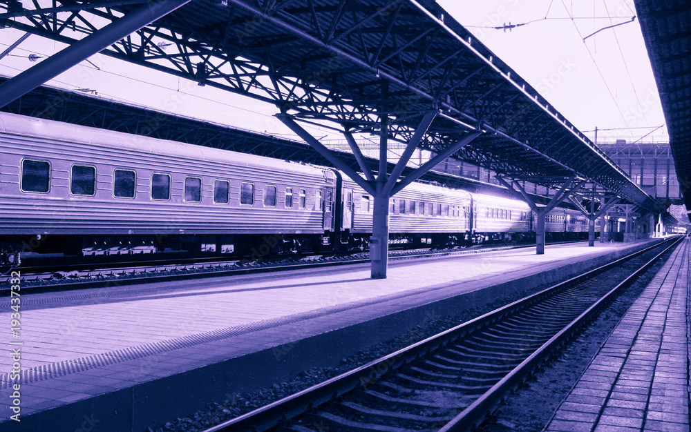 Surrealistic ultra violet toned perspective image of the railway station with railway tracks and train. Surrealistic ultra violet toned perspective image of the railway station with railway tracks and train.