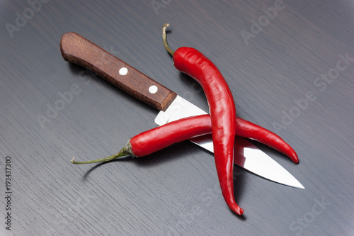  red chili peppers and knife on the kitchen table