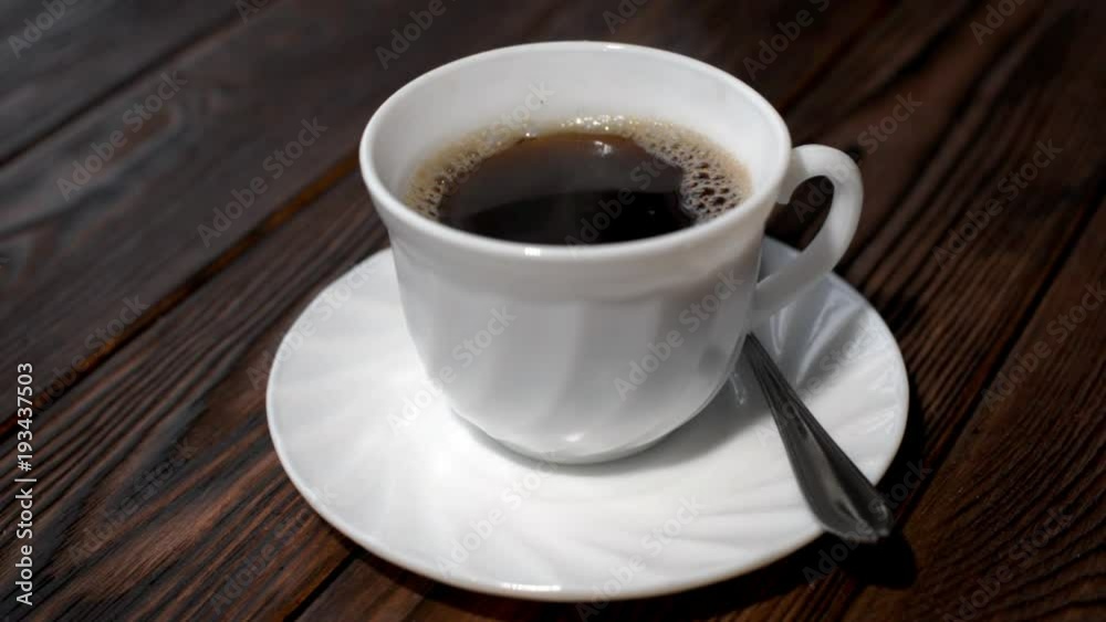 A cup of hot coffee stands on a wooden table A cup of hot coffee stands on a wooden table