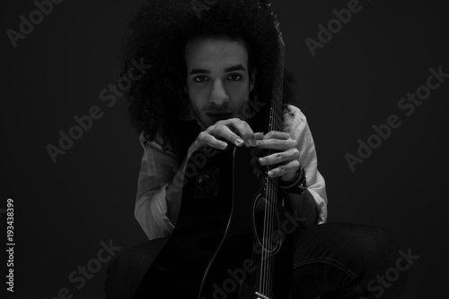 black and white portrait of young musician with acoustic guitar looking at camera