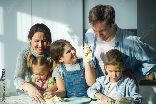 Large family prepares something of dough.
