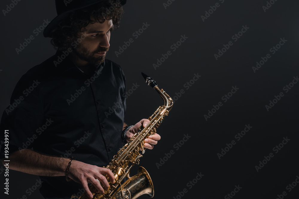 Naklejka premium young musician playing saxophone on black