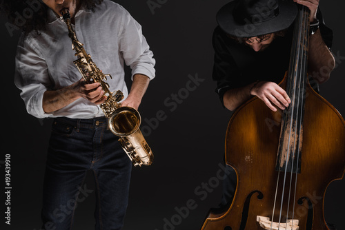 duet of jazzmen playign cello and sax on black